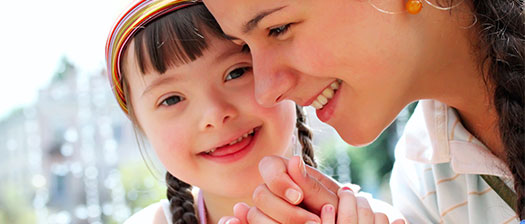Close up of young person with disability smiling towards the camera together with their support person, they are holding hands