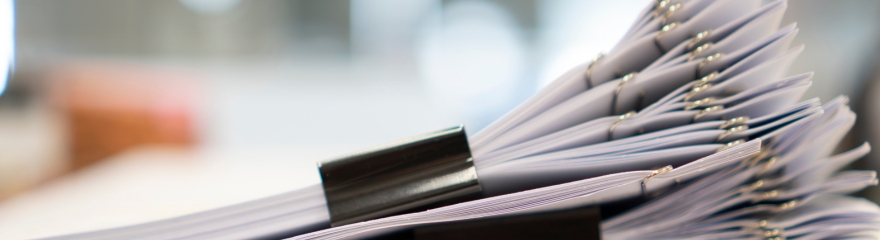 A pile of documents sit on a desk