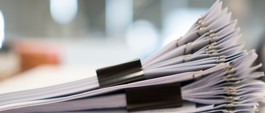 A pile of documents sit on a desk