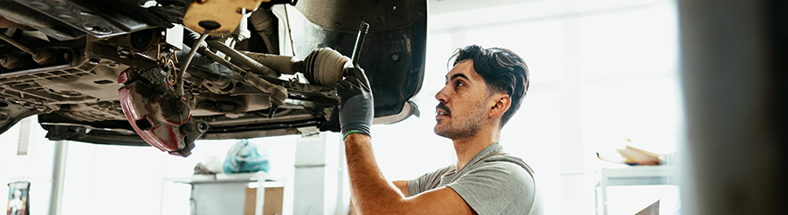 A young man is working on a car in a mechanic's garage