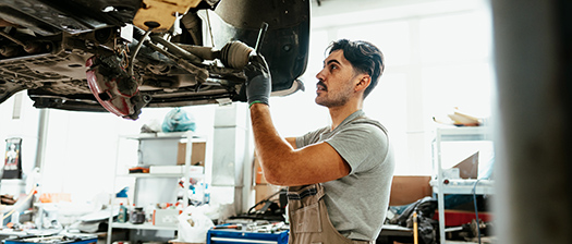 A young man is working on a car in a mechanic's garage