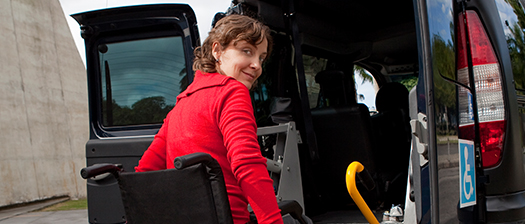A person in a wheelchair looking back over their shoulder while entering a vehicle