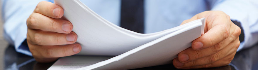 A close up of a person in business attire holding a stack of papers