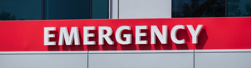 Large red sign on a hospital building that reads Emergency
