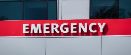 Large red sign on a hospital building that reads Emergency