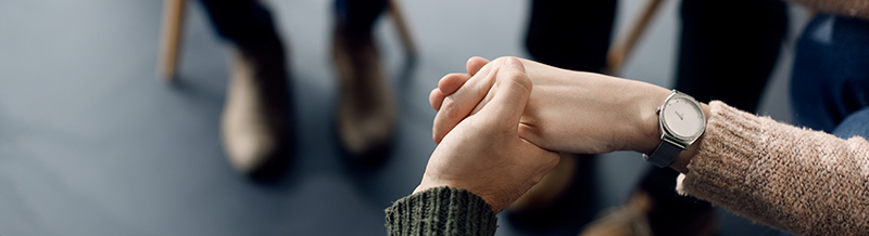 Close up of two people holding hands in a show of support
